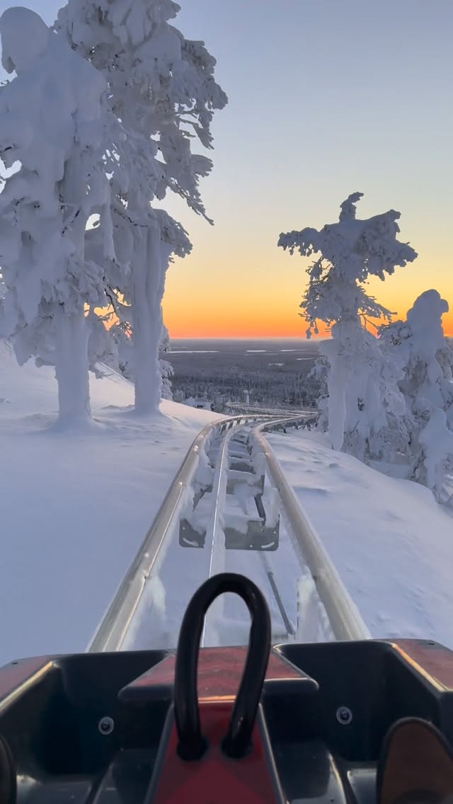 Snowy rollercoaster track at sunset in winter landscape.