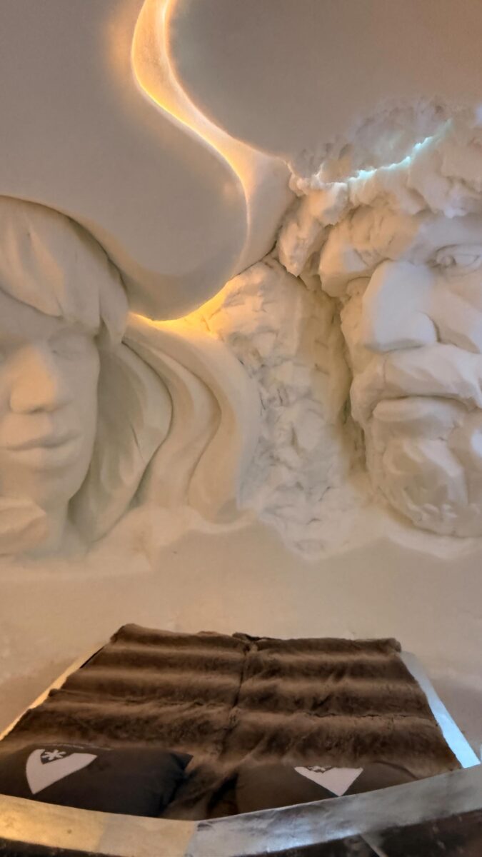 Sculpted faces in ice above fur-clad bed