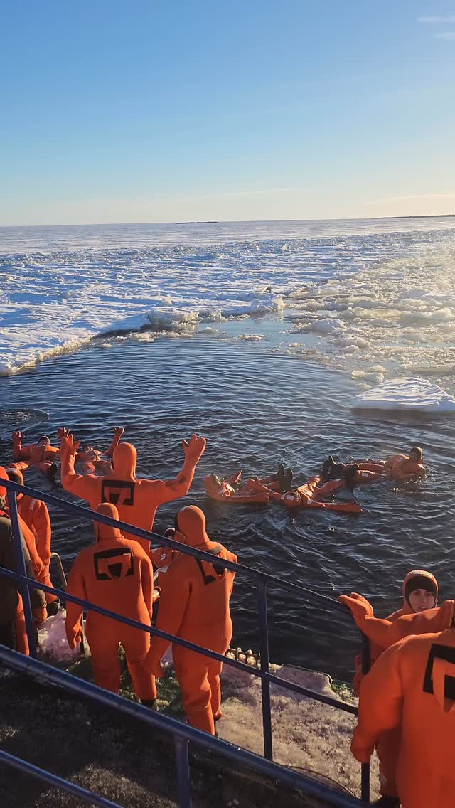People in orange suits in icy water