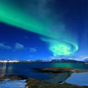 Aurora Borealis over snowy landscape and water
