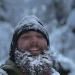 Person with snowy beard in winter landscape.