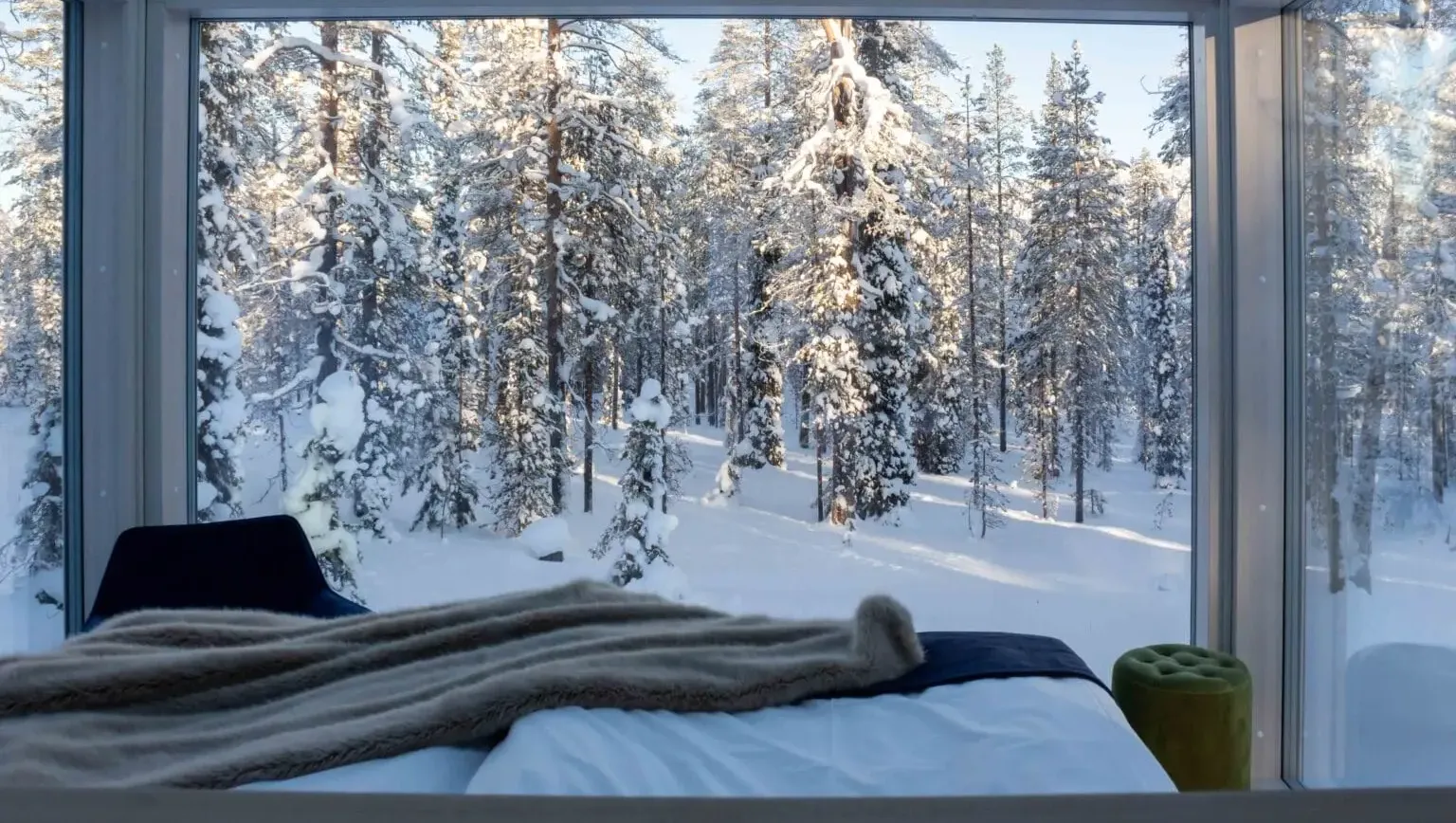 Bedroom with panoramic window overlooking snowy forest