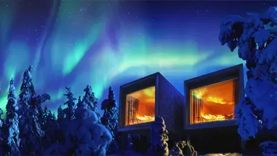 Modern cabin under northern lights in snowy forest