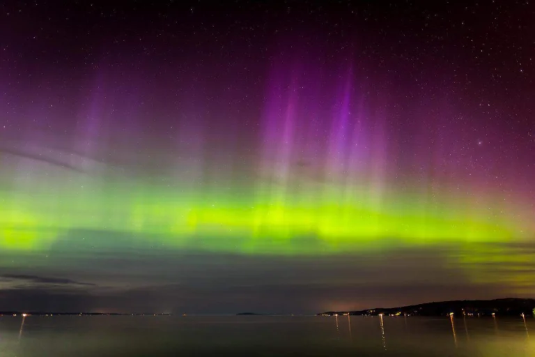 Green and purple northern lights over water