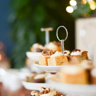 Tiered stand with small frosted cakes and nuts