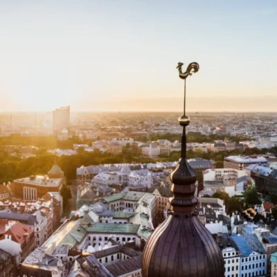 Sunset over historic city with rooster-topped spire