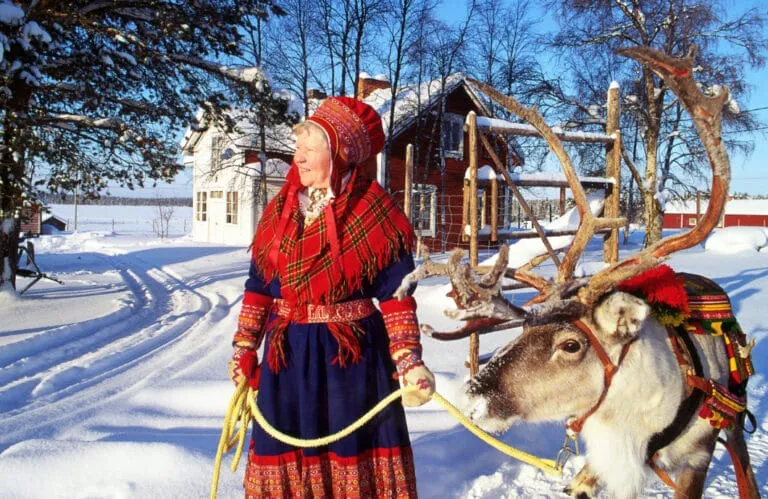 Woman in traditional dress with reindeer in snow