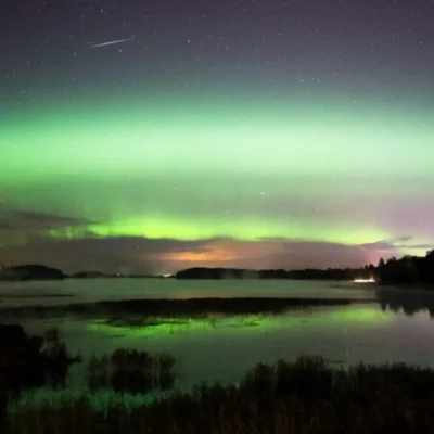 Green aurora over calm lake at night