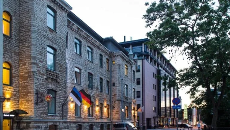 Stone embassy building with flags at dusk