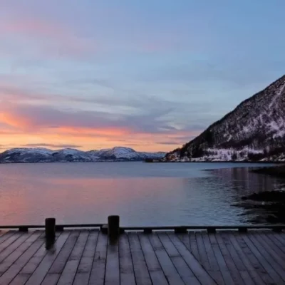Snowy mountains at sunset over calm lake