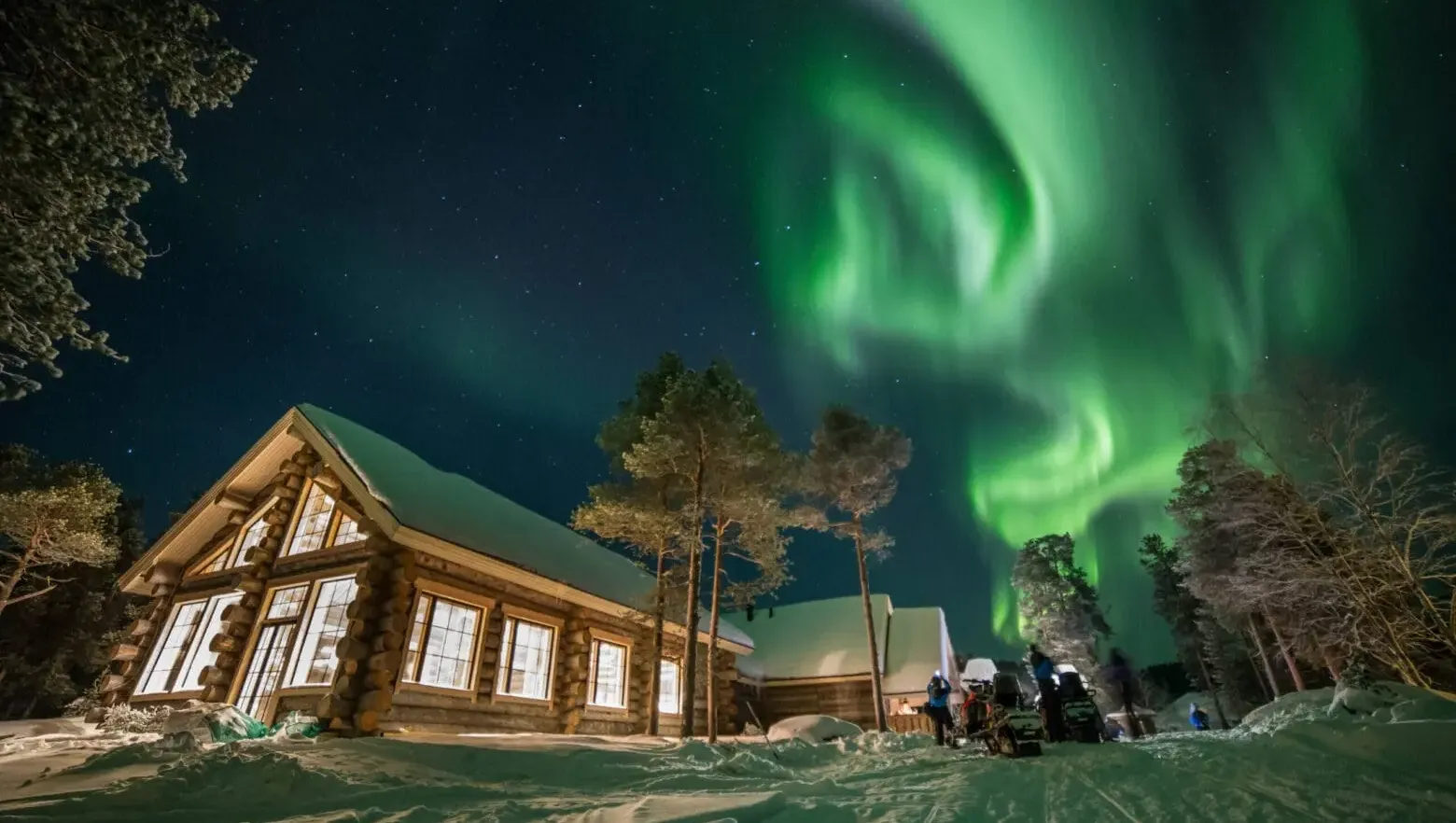 Northern lights over snowy log cabin at night